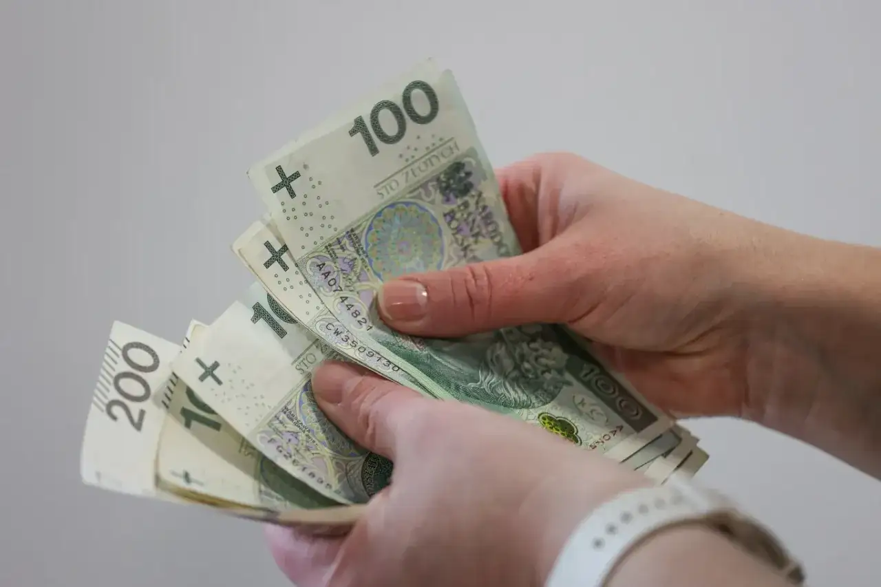 Dłonie trzymające polskie banknoty 100 i 200 zł.