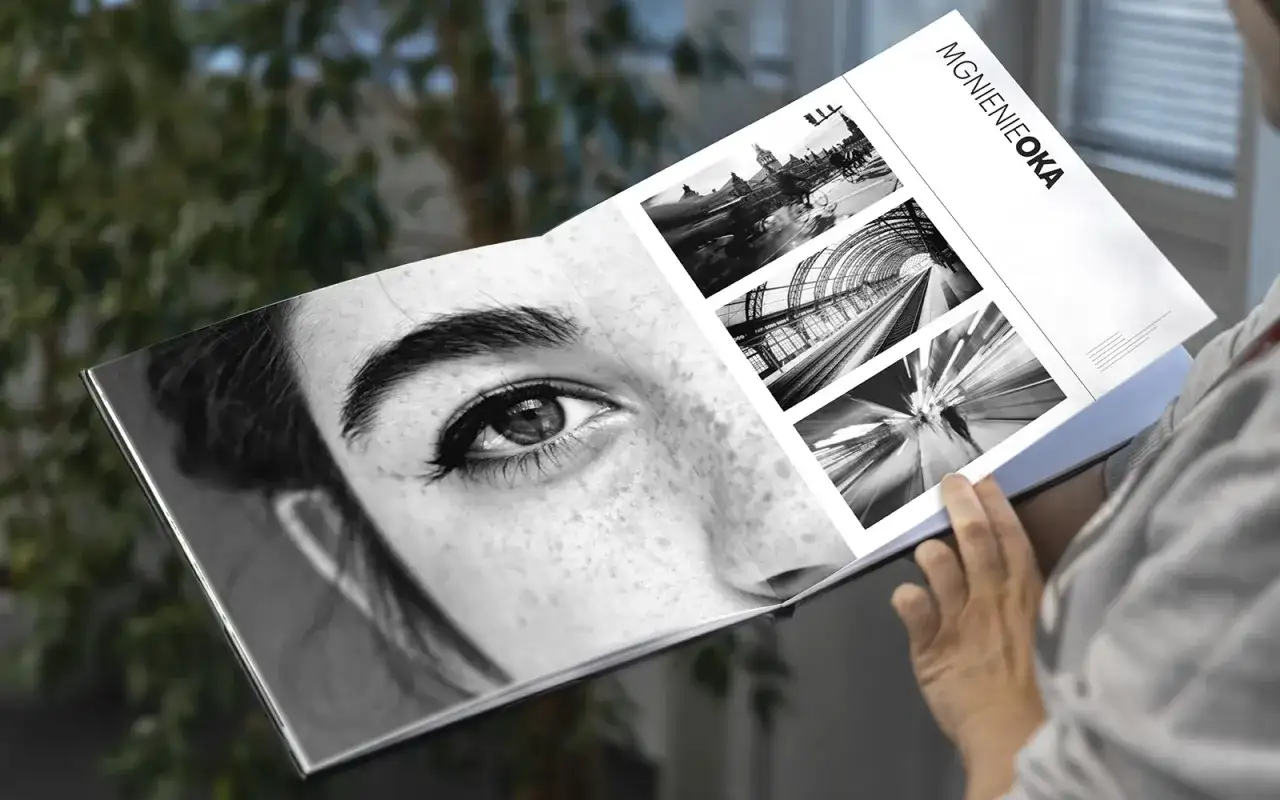 Osoba przegląda album "Mgnienie Oka", gdzie obok zbliżenia oka kobiety znajdują się czarno-białe fotografie miejskich krajobrazów i ruchu.