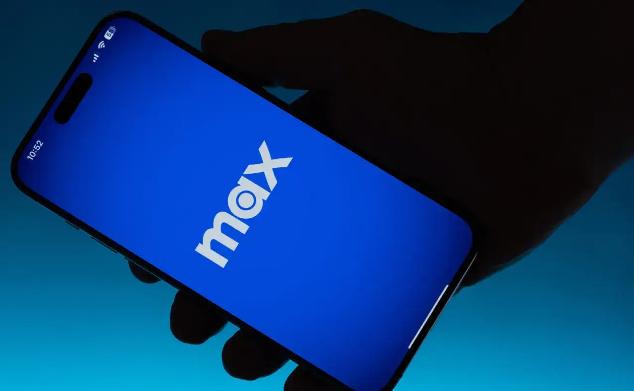 Dłoń trzyma smartfon z niebieskim ekranem i białym logo Max.