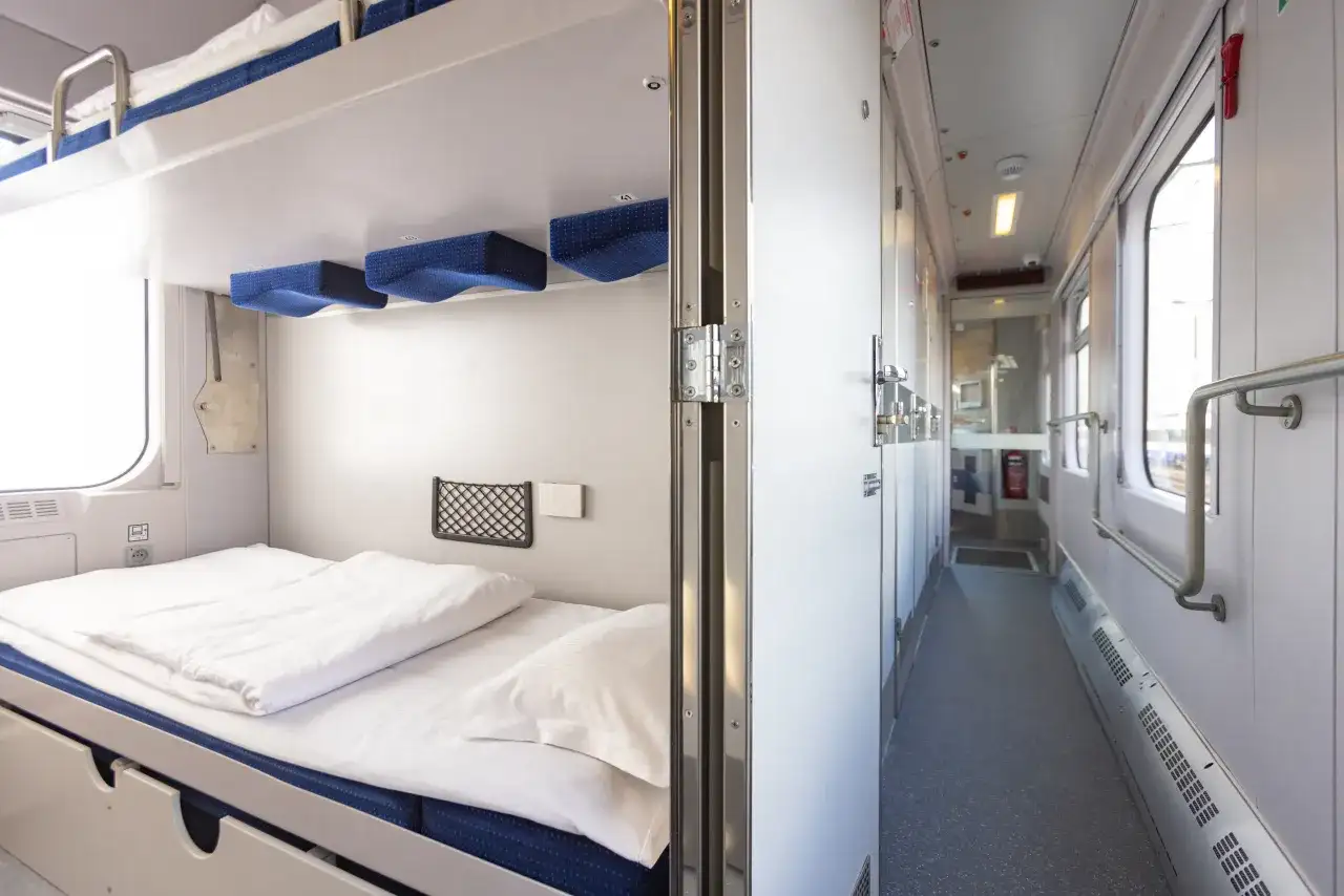 Wnętrze wagonu sypialnego z piętrowymi łóżkami. Zastanawiasz się, ile kosztuje wagon sypialny? To wygodne miejsce na podróż.