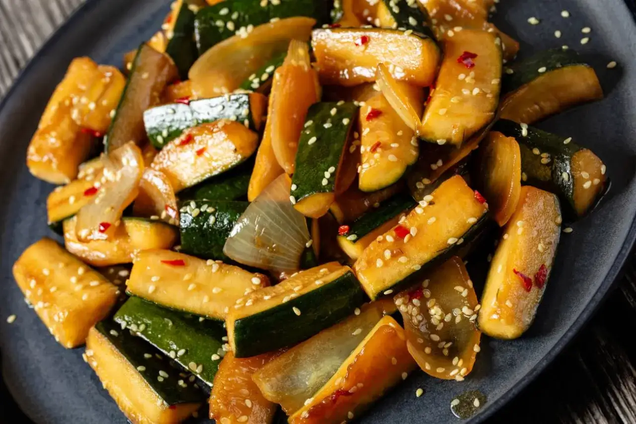 Smażona cukinia z cebulą i sezamem, posypana płatkami chili. Świetny pomysł, co ugotować z cukini, gdy masz jej dużo!