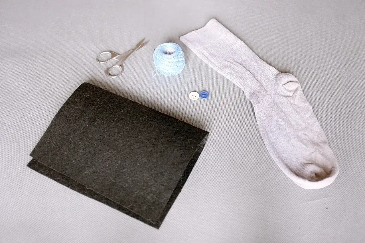 Materiały do zrobienia kotka ze skarpetki: skarpetka, nożyczki, włóczka, guziki i czarny filc.