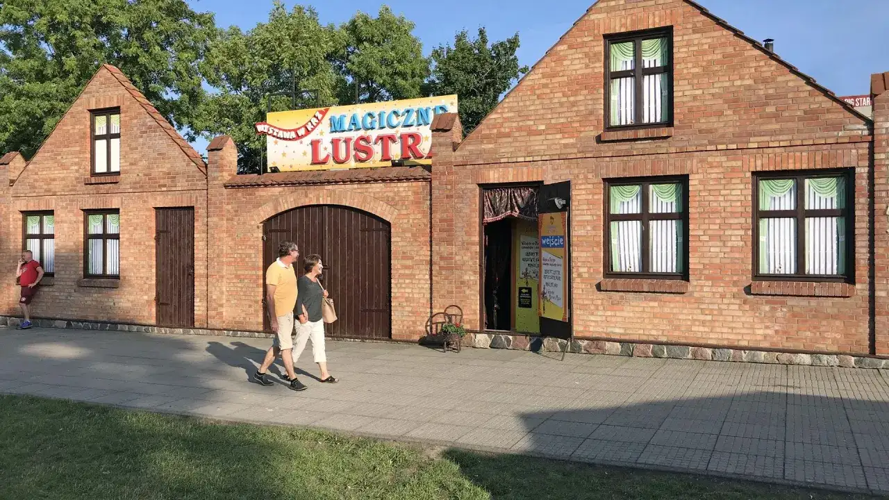 Para spaceruje obok budynku z napisem "Magiczne Lustra Łeba".