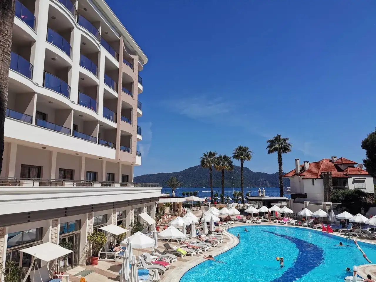 Fajny hotel nad morzem z basenem i palmami. Słoneczny dzień, idealny na wakacje.