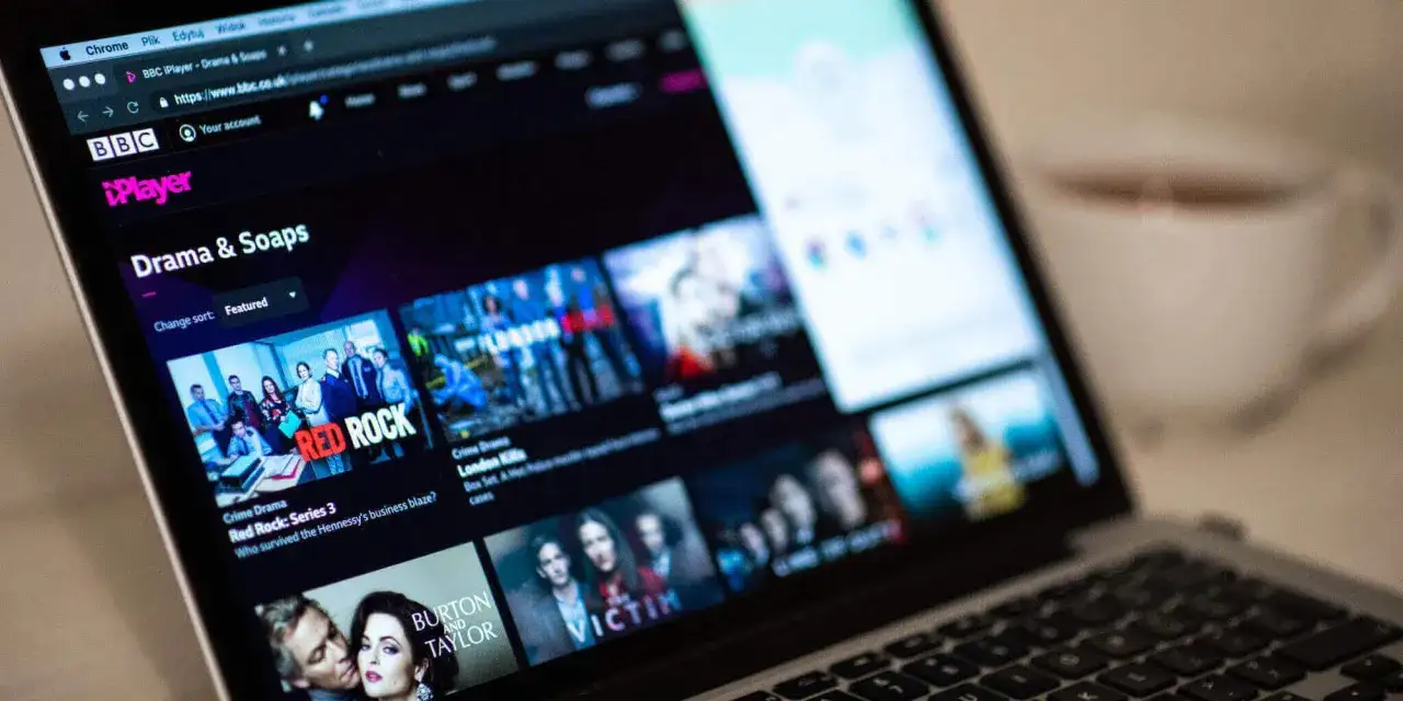 Ekran laptopa z interfejsem BBC iPlayer Polska, wyświetlający kategorie "Drama & Soaps" i okładki seriali takich jak "Red Rock".