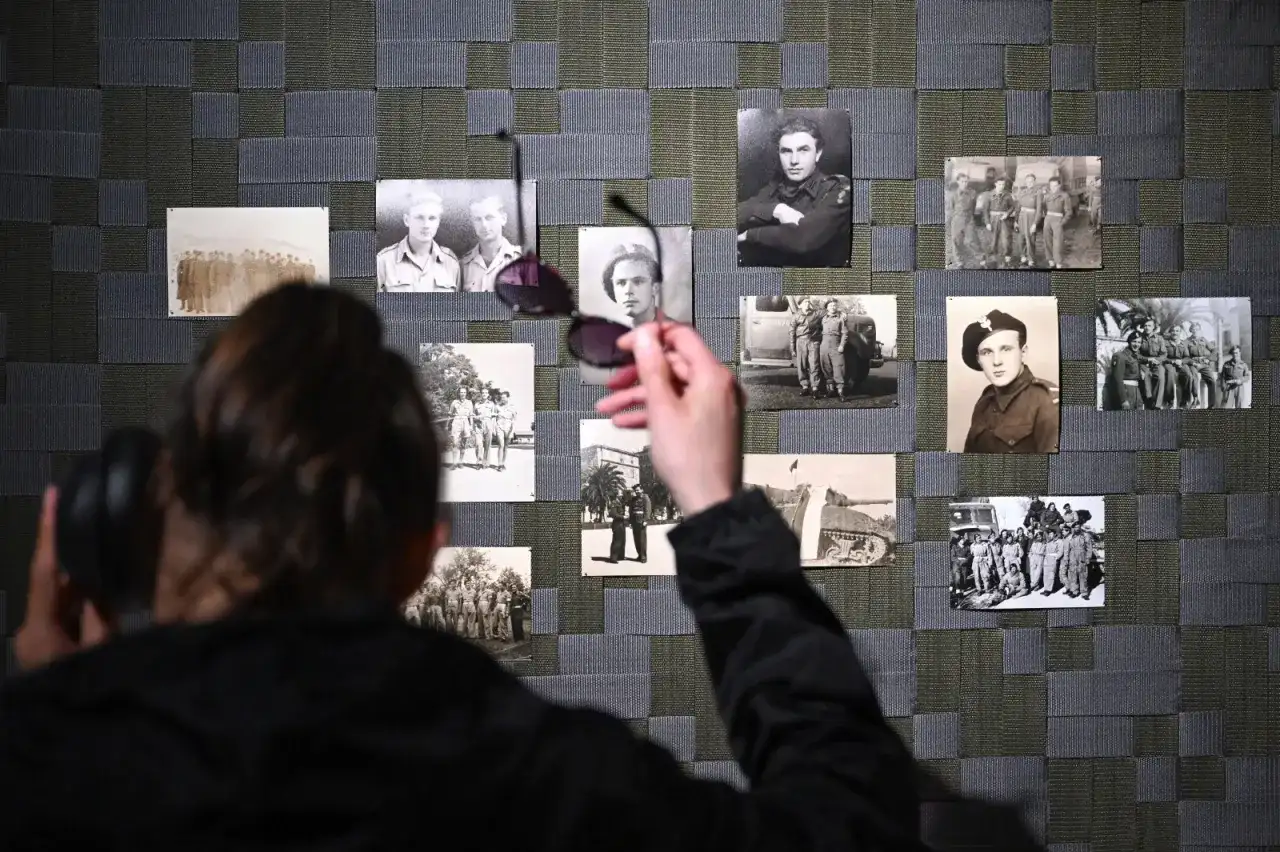 Osoba z słuchawkami na uszach ogląda wystawę zdjęć z czasów wojny. Czy wśród nich jest dziadek Donalda Tuska?