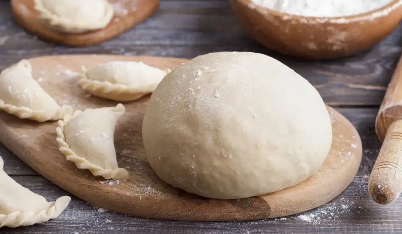 Świeże ciasto na pierogi i kilka uformowanych pierożków. Zastanawiasz się, czy ciasto na pierogi można zrobić dzień wcześniej? Tak, można!