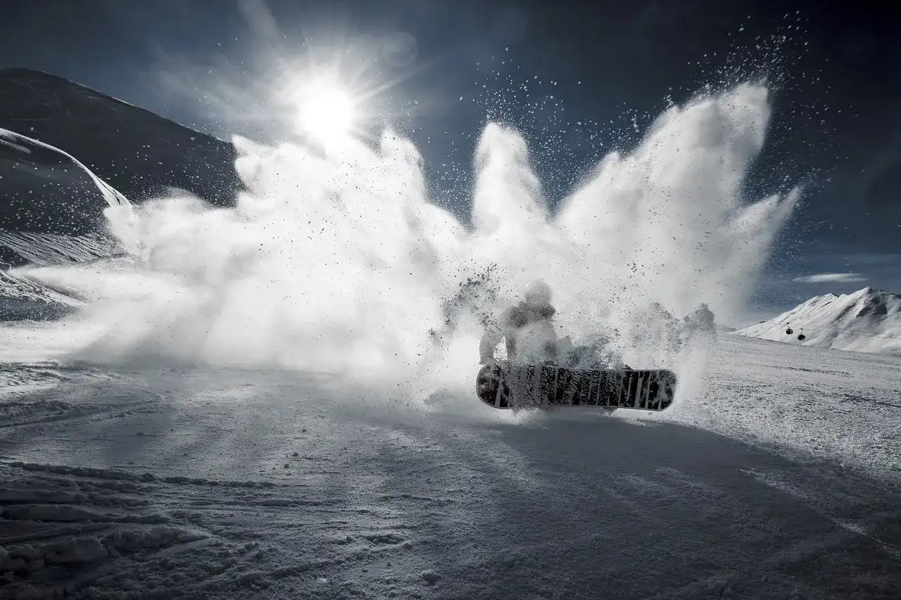 Snowboardzista wykonujący obrót 360 stopni, wzbijając chmurę śniegu.