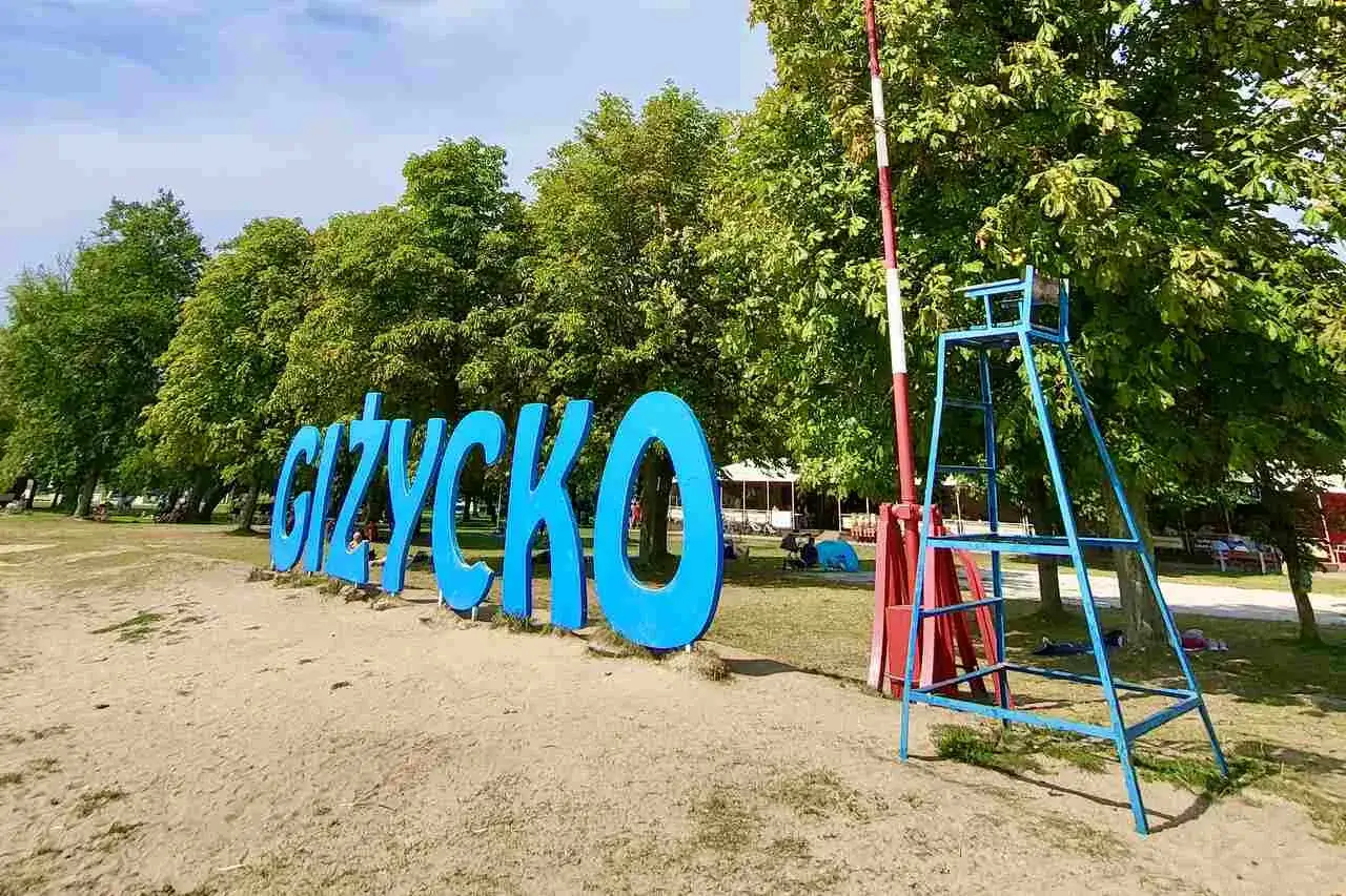 Napis GIŻYCKO na plaży, obok ratownicza wieża. Idealne miejsce na wakacje, mnóstwo giżycko atrakcje dla dzieci.