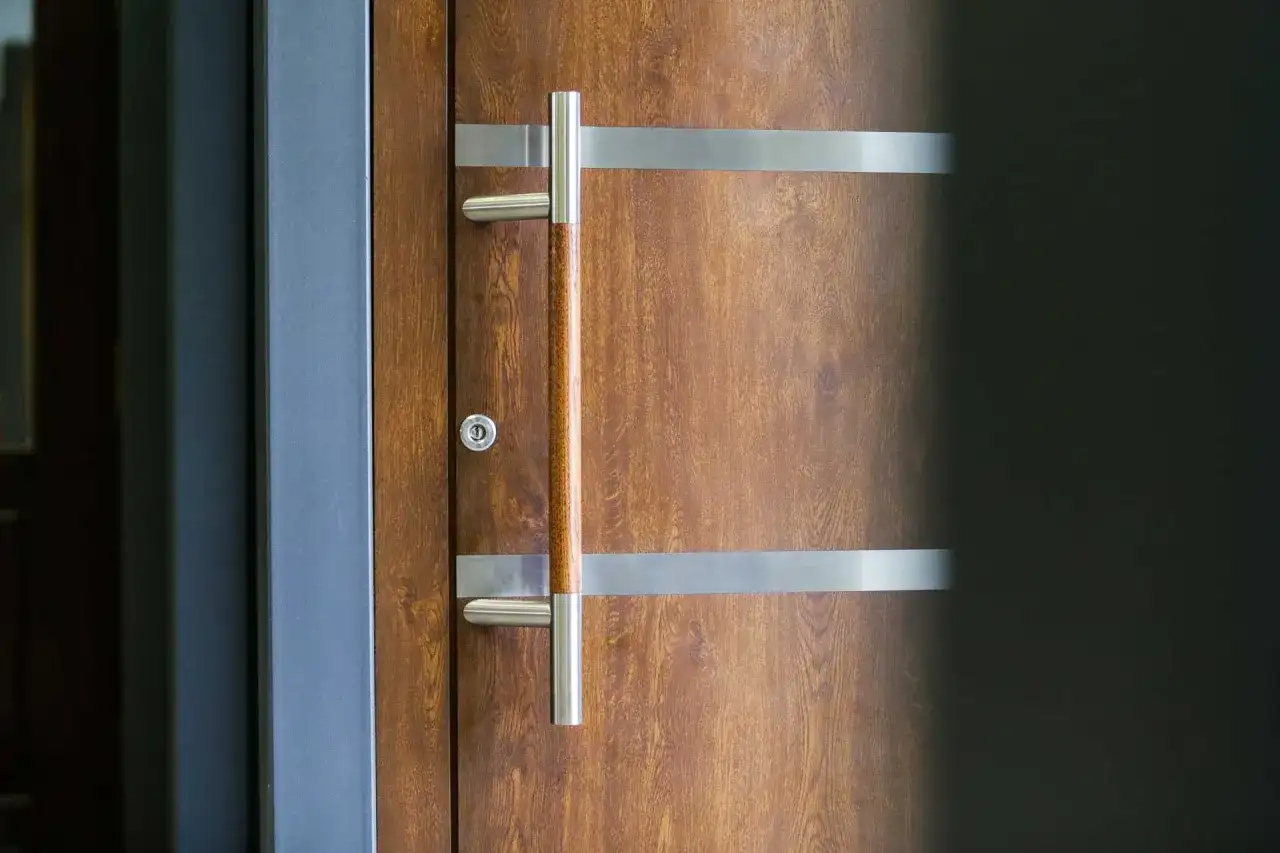 Eleganckie drzwi z meranti z nowoczesnym, metalowym uchwytem i ozdobnymi listwami.