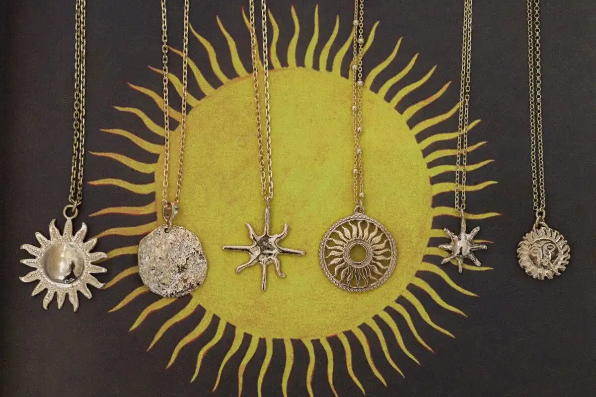 Pięć złotych naszyjników z motywem słońca. Symbol słońca znaczenie: życie, moc, energia.