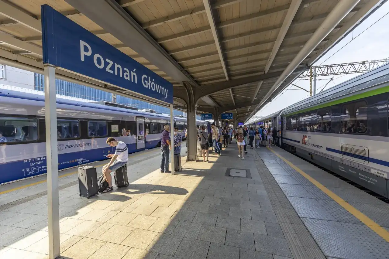 Peron na dworcu Poznań Główny z pociągami i pasażerami.