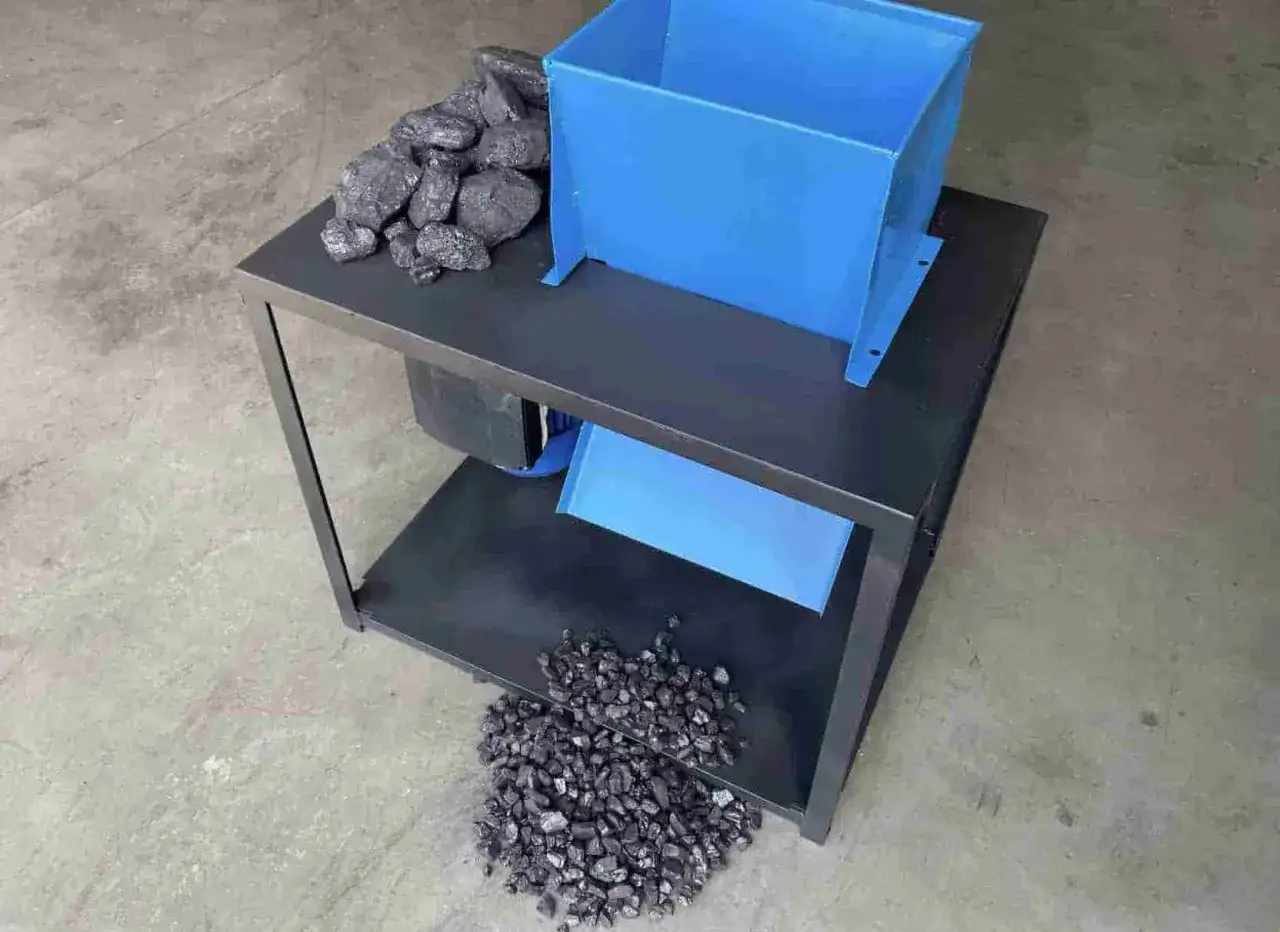 Maszyna do kruszenia węgla z niebieskim zasobnikiem i pokruszonym węglem.