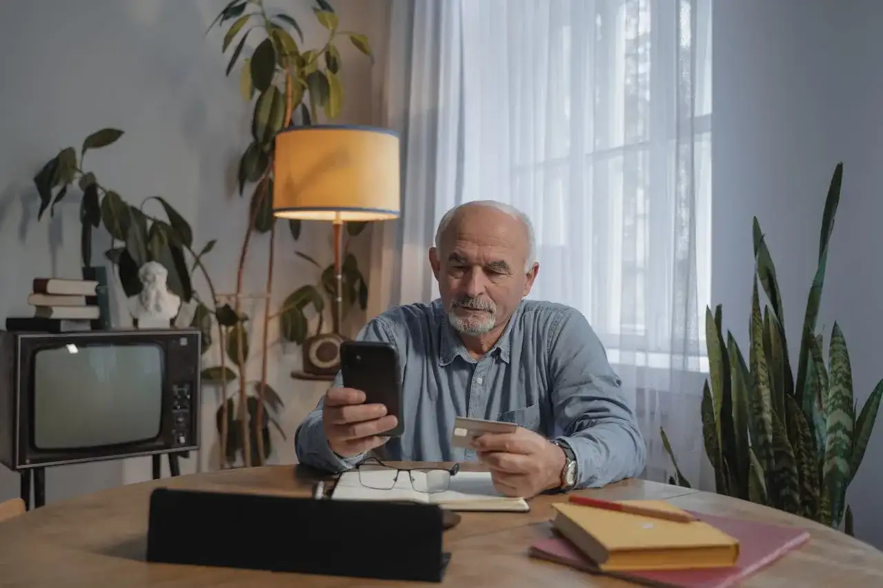 Starszy pan sprawdza w telefonie, ile kosztuje przedłużenie w lombardzie.