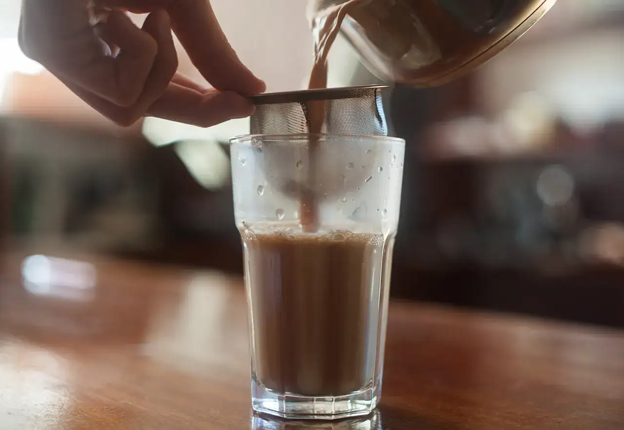 Przelewanie aromatycznego napoju przez sitko do szklanki.