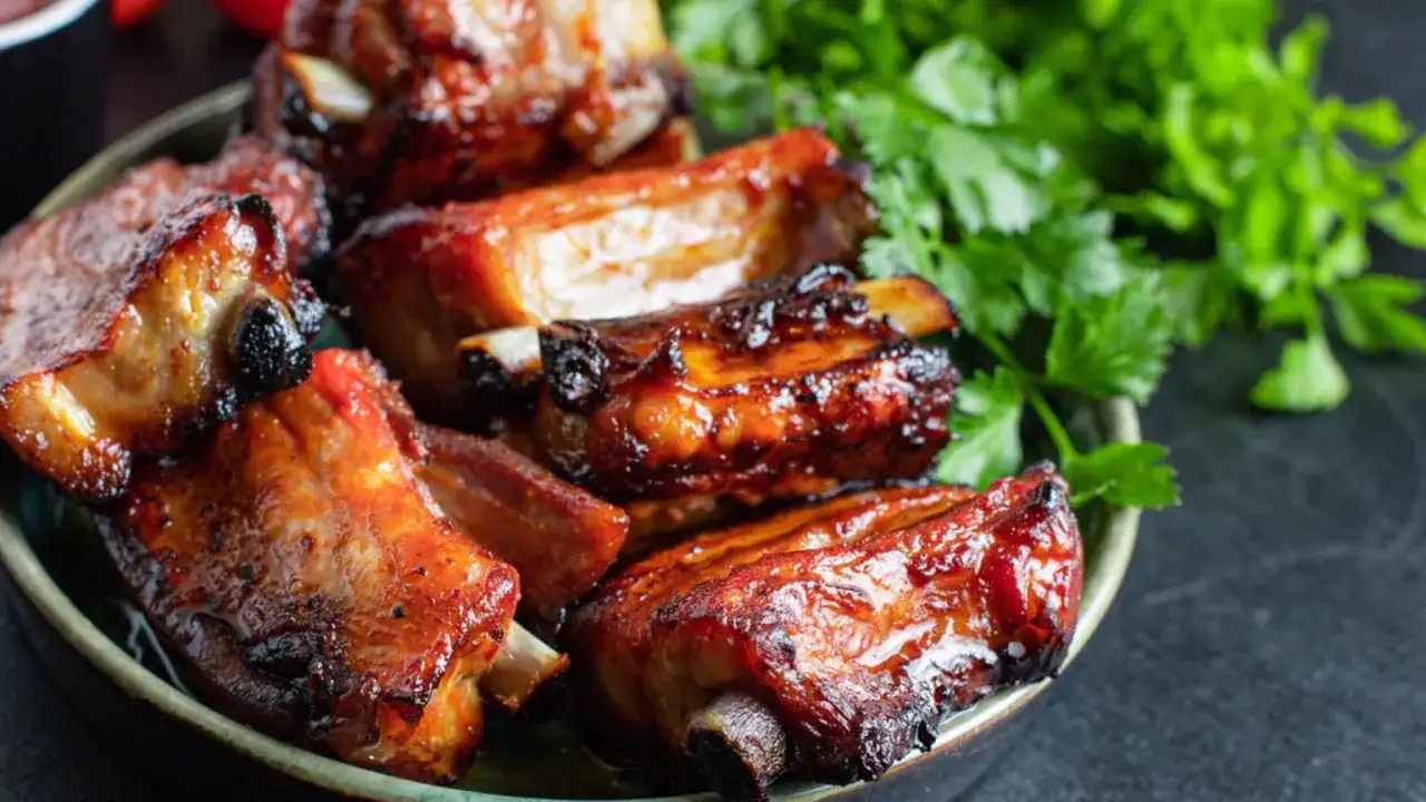 Soczyste, glazurowane żeberka wieprzowe na talerzu, z gałązkami świeżej pietruszki. Idealne pytanie: co ugotować na żeberkach?