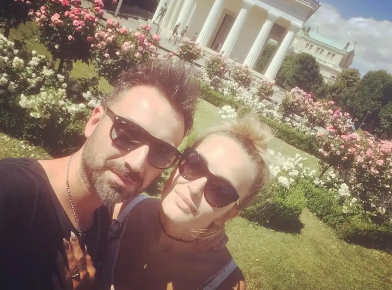 Mateusz Ziółko z żoną w słoneczny dzień wśród kwitnących róż.