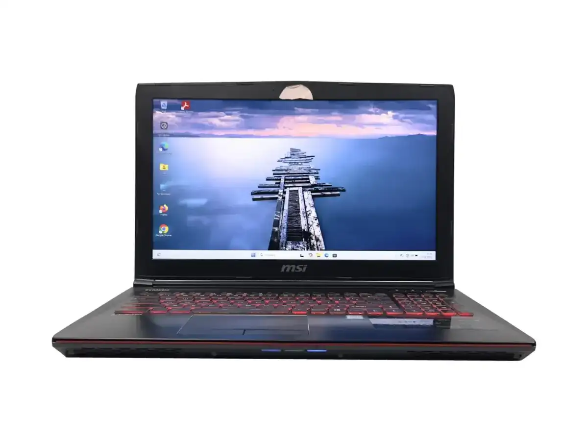 Czarny laptop MSI z podświetlaną na czerwono klawiaturą. Na ekranie widok na drewniane molo. Zastanawiasz się, jaki Windows do starego laptopa?