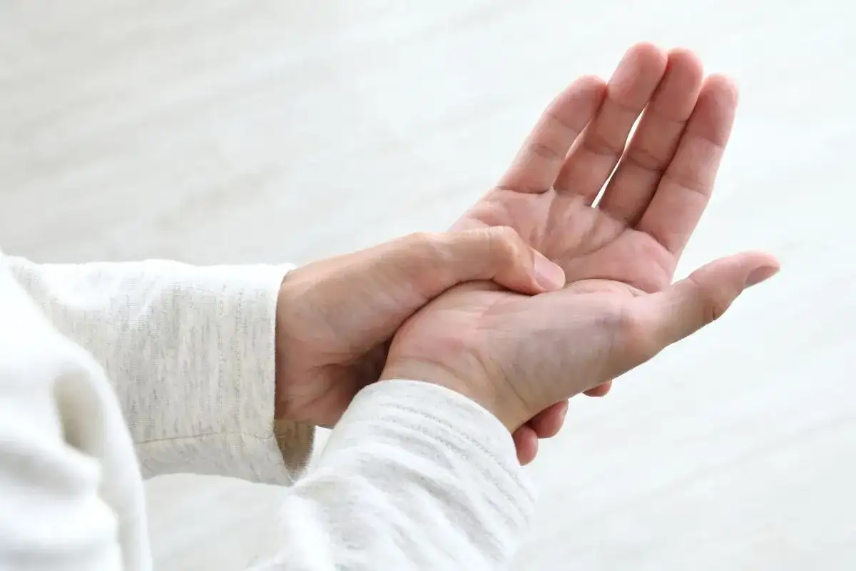 Dłoń masuje punkt między kciukiem a palcem wskazującym, co może pomóc w łagodzeniu bólu głowy dzięki akupresurze.