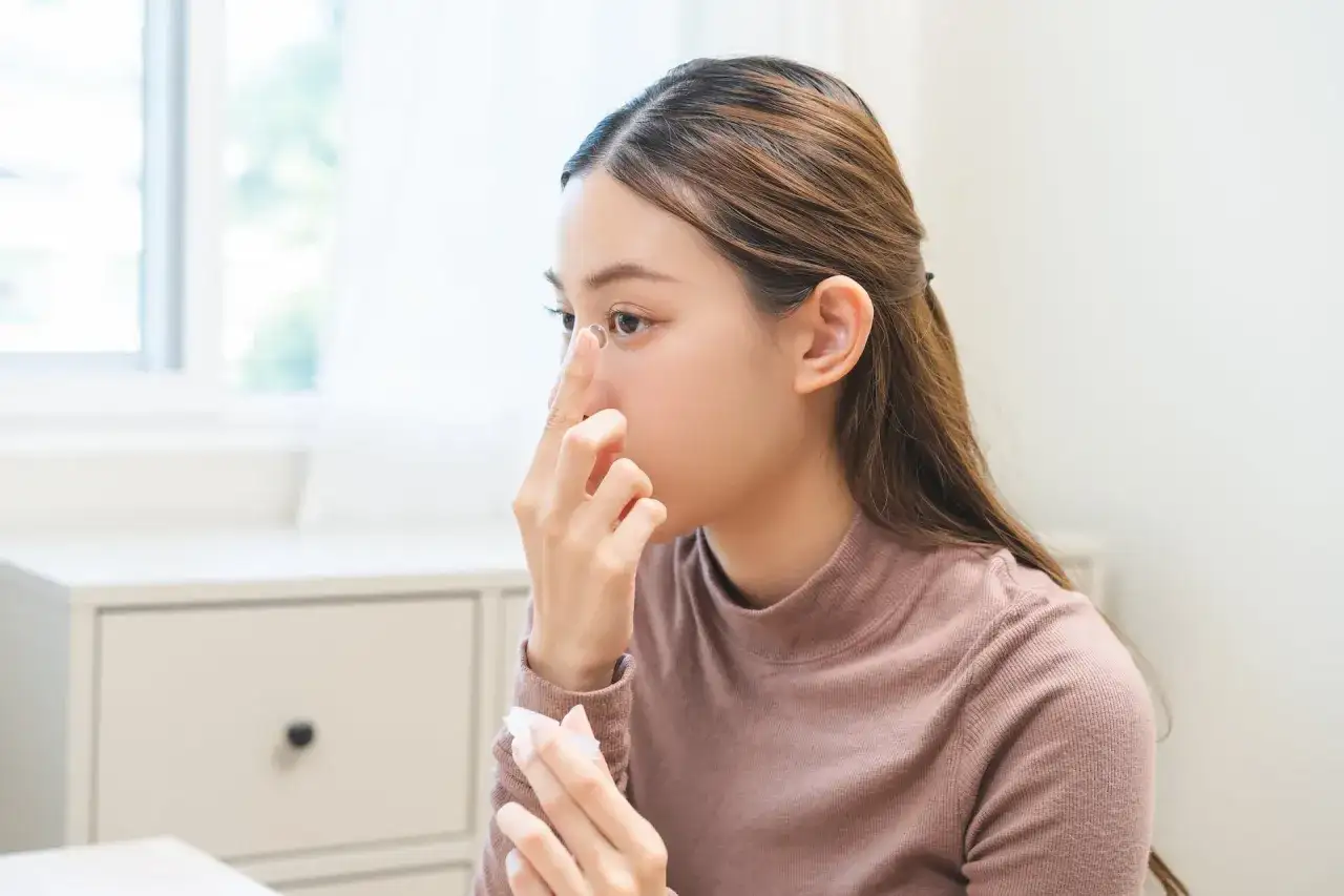 Kobieta zakłada soczewkę kontaktową na oko.