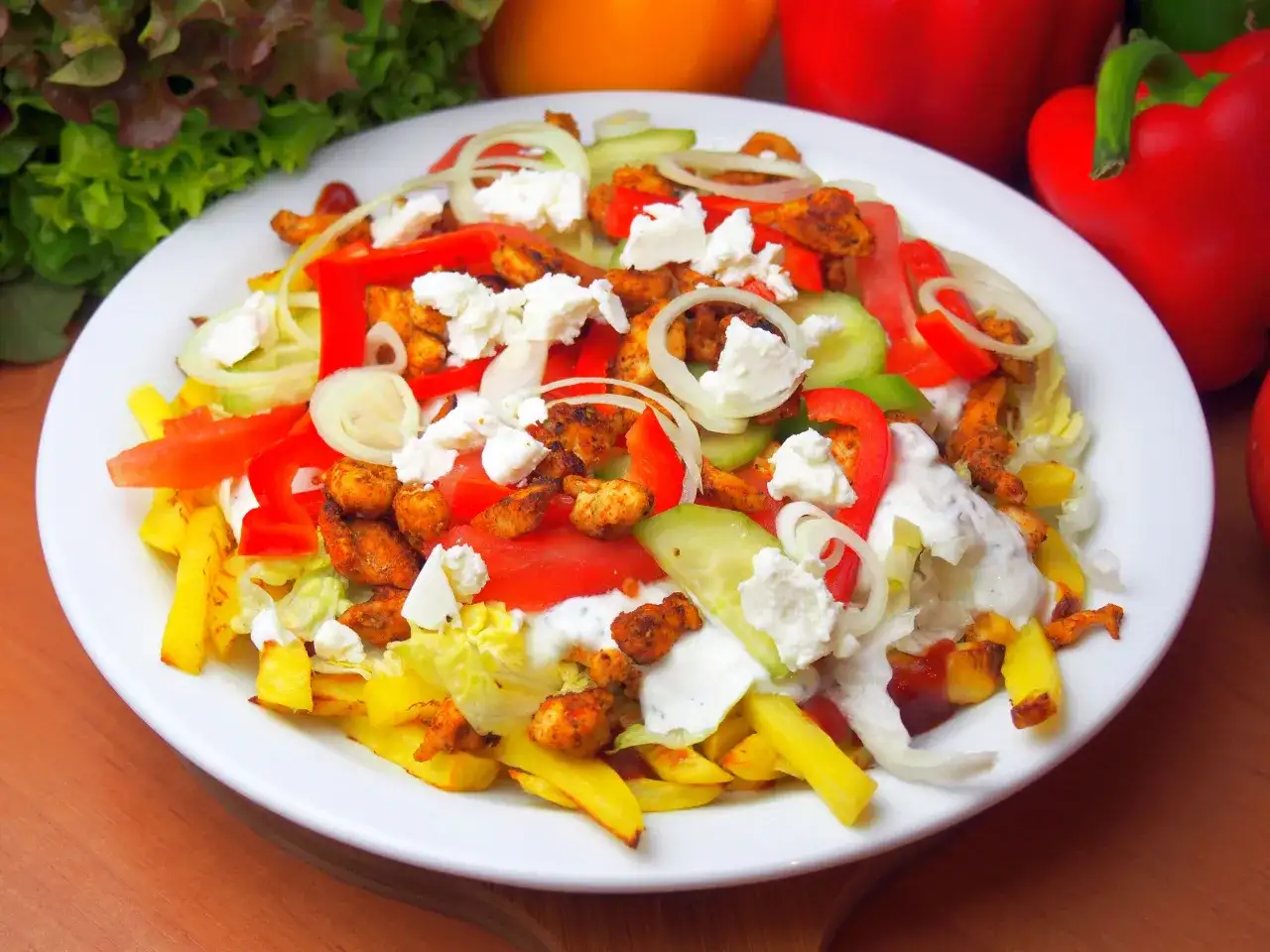 Talerz z kebabem, frytkami, warzywami i serem feta, polany sosem.