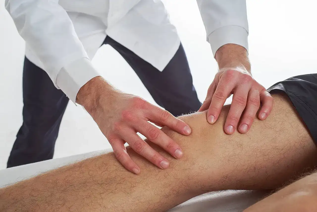 Terapeuta wykonuje delikatne ruchy na nodze pacjenta, co ilustruje, na czym polega terapia Bowen'a.