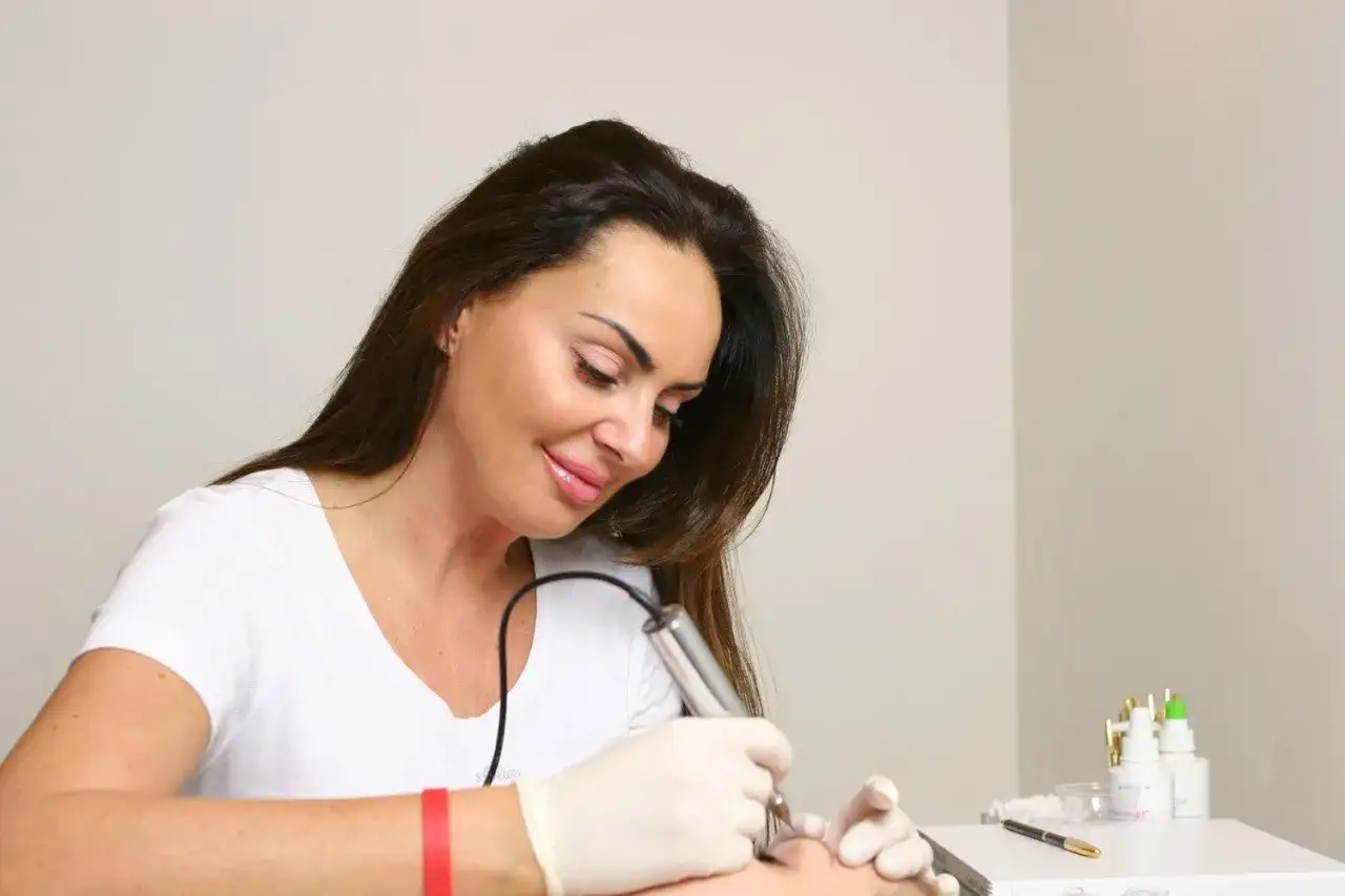 Kobieta po 40. z zadbaną cerą, wykonująca makijaż permanentny. Sekret młodego wyglądu.