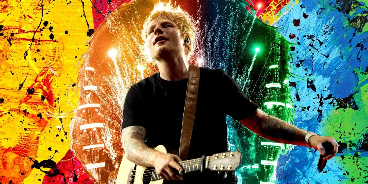 Ed Sheeran gra na gitarze na tle kolorowych eksplozji. Wyobraź sobie, kiedy Ed Sheeran zagra koncert w Polsce!