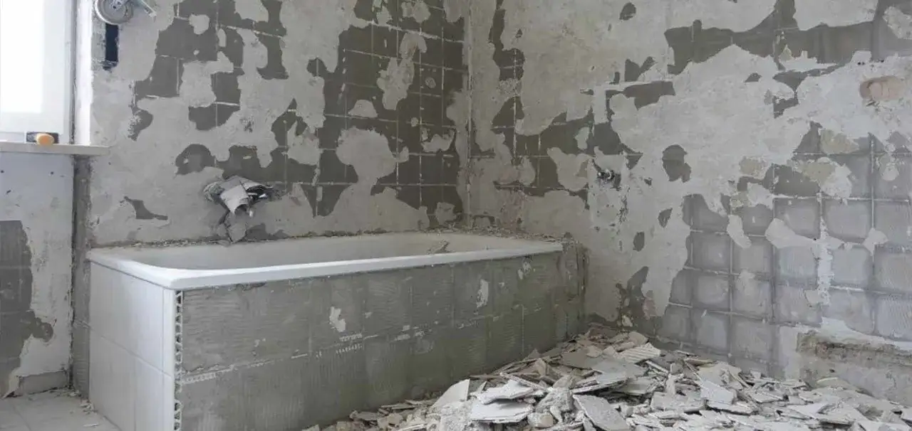 Łazienka w trakcie remontu, z odsłoniętymi ścianami i gruzem.