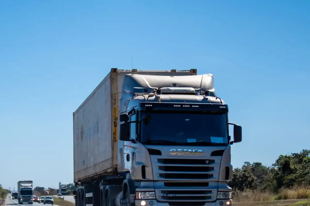 Ciężarówka Scania z kontenerem na autostradzie pod błękitnym niebem.
