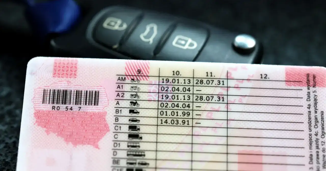 Zbliżenie na polskie prawo jazdy z datami ważności kategorii, obok kluczyki samochodowe. Sprawdź, prawo jazdy na ile lat jest ważne.
