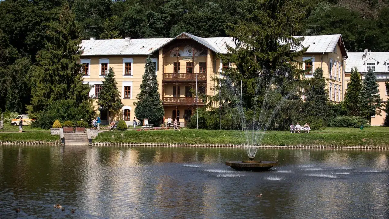 Piękny budynek sanatorium godne polecenia, z fontanną i stawem, otoczony zielenią.