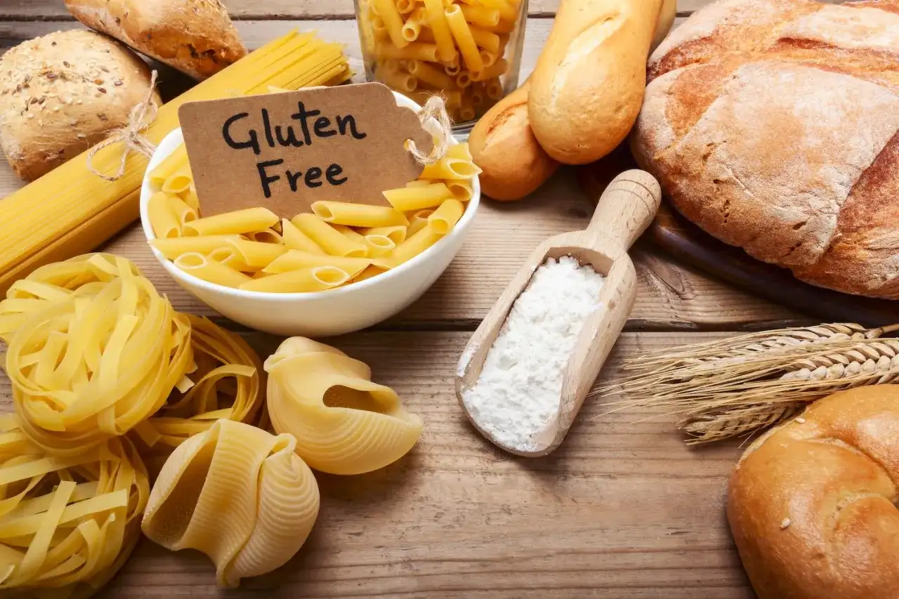 Różne rodzaje makaronów i pieczywa, a także mąka i kłosy zbóż. Etykieta "Gluten Free" sugeruje dyskusję: czy gluten jest zdrowy?
