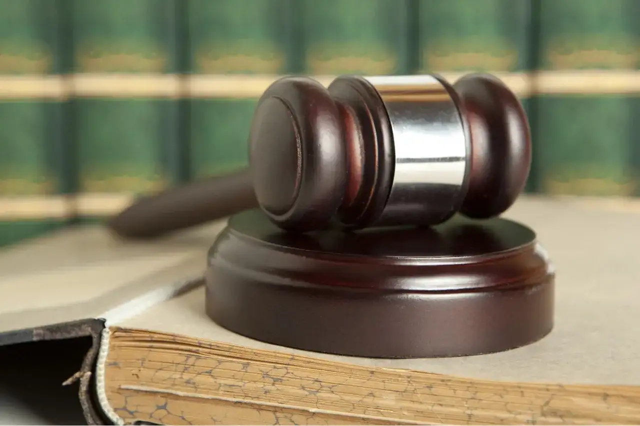 Młotek sędziowski na starej księdze. Dowiedz się, jak odpowiedzieć na pozew i bronić swoich praw.