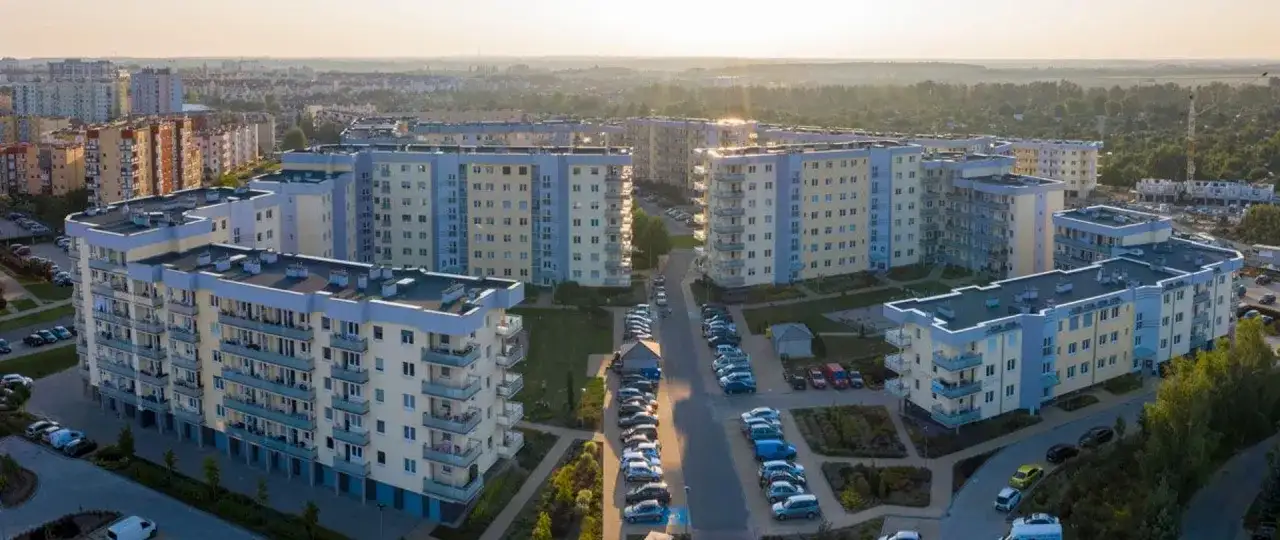Widok z lotu ptaka na osiedle bloków mieszkalnych z balkonami i parkingami.