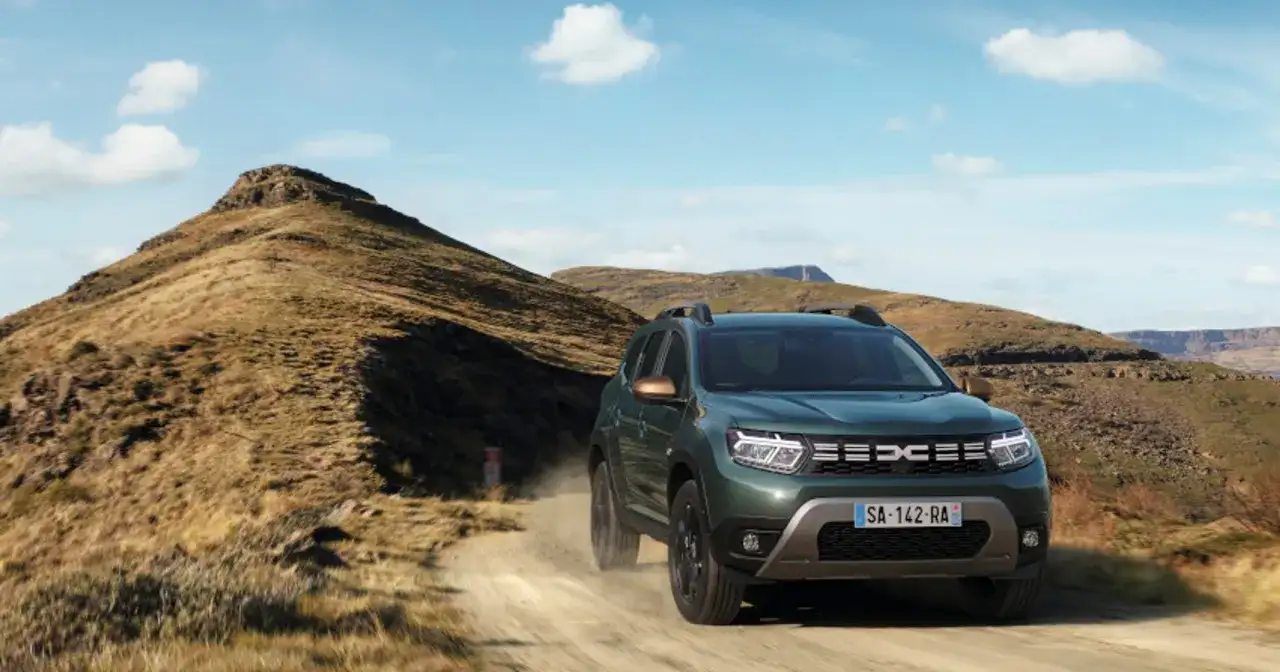 Zielony Dacia Duster off road pokonuje piaszczystą drogę wśród skalistych wzgórz.