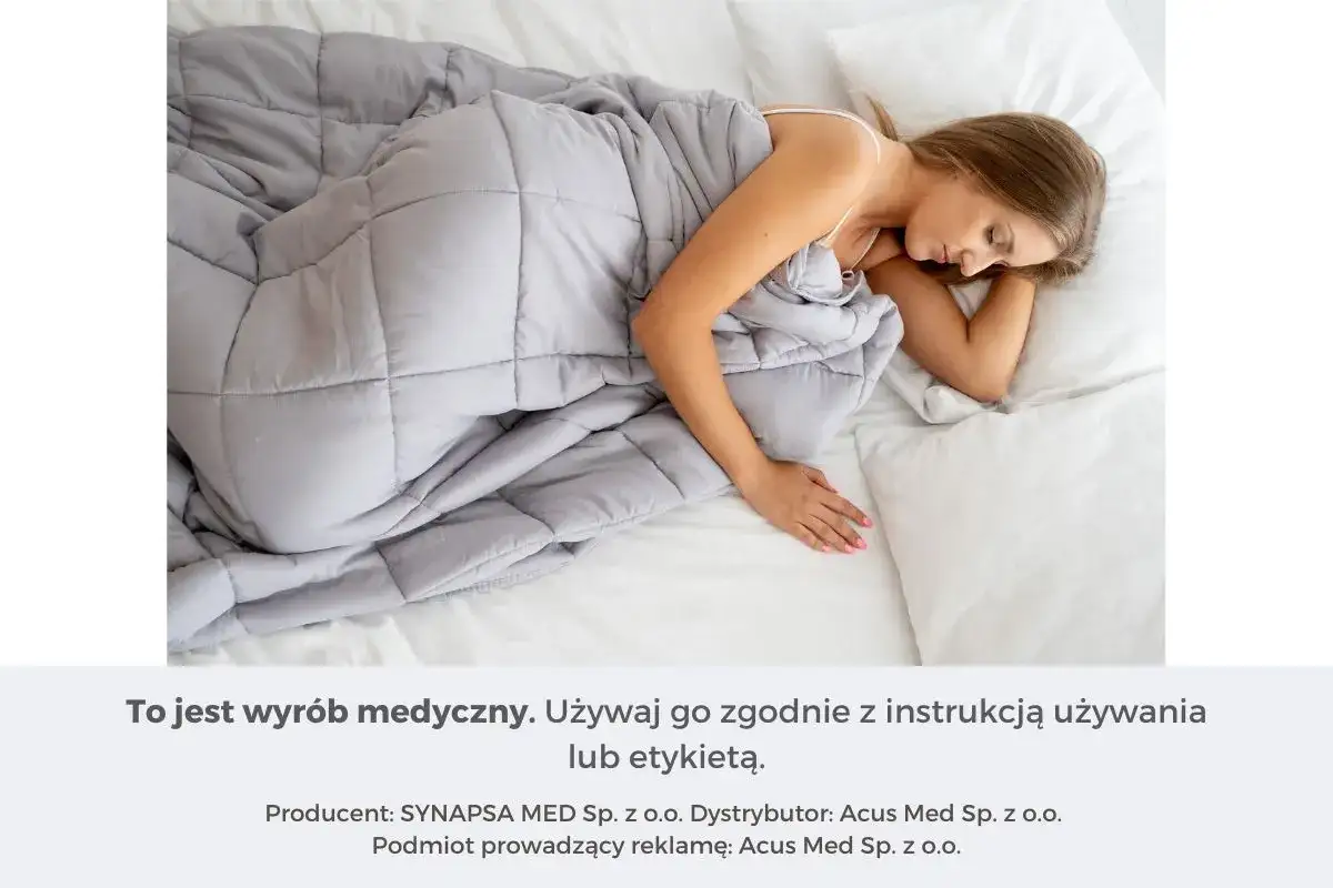 Kobieta śpi pod szarą kołdrą obciążeniową. Dowiedz się, jak dobrać idealną kołdrę obciążeniową dla siebie.