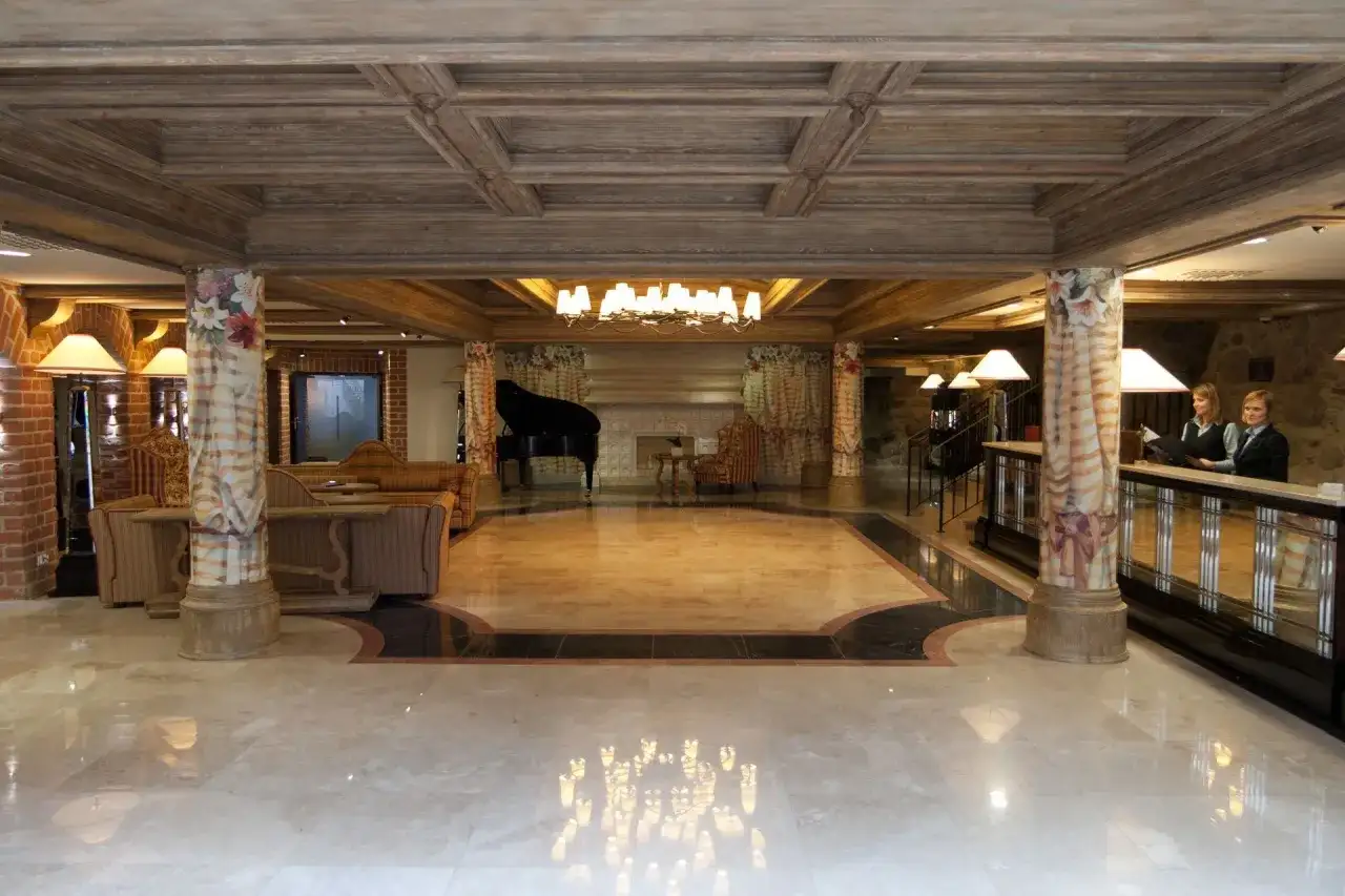 Eleganckie lobby hotelowe z fortepianem, recepcją i dwoma pracownikami.