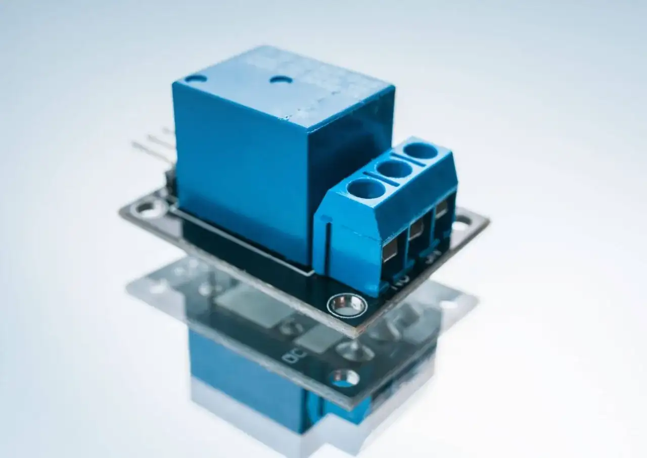 Niebieski przekaźnik bistabilny na płytce drukowanej, z zaciskami śrubowymi do podłączenia przewodów.