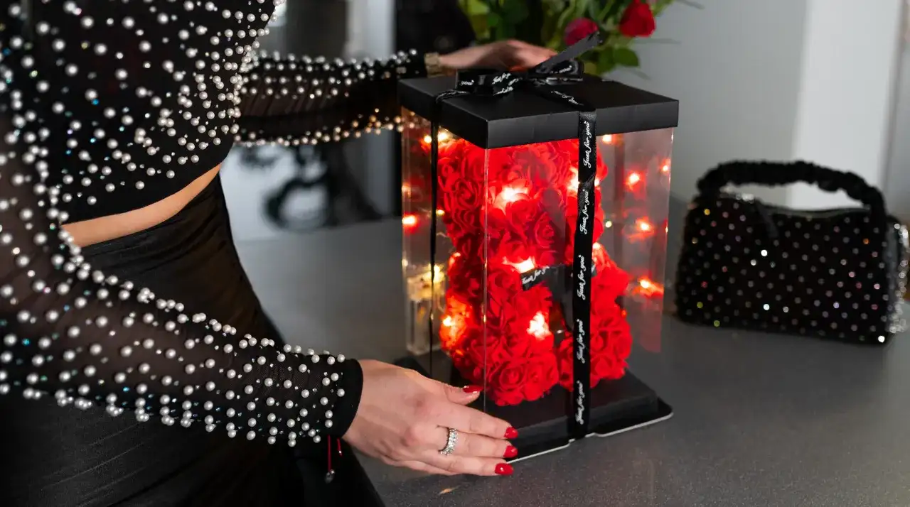 Miś z czerwonych róż w przezroczystym pudełku, ozdobiony lampkami LED.