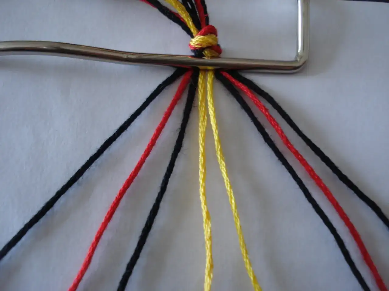 Wzory krok po kroku: czarne, czerwone i żółte muliny zaczynają tworzyć bransoletkę.