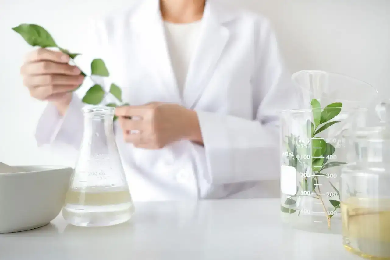 Biolog w białym fartuchu bada rośliny w laboratorium. Zastanawiasz się, ile zarabia biolog?