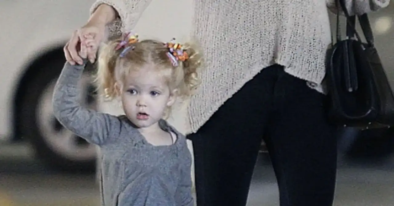 Mała dziewczynka z blond włosami w kucykach, trzymana za rękę przez dorosłego. To jedno z dzieci Amy Adams.