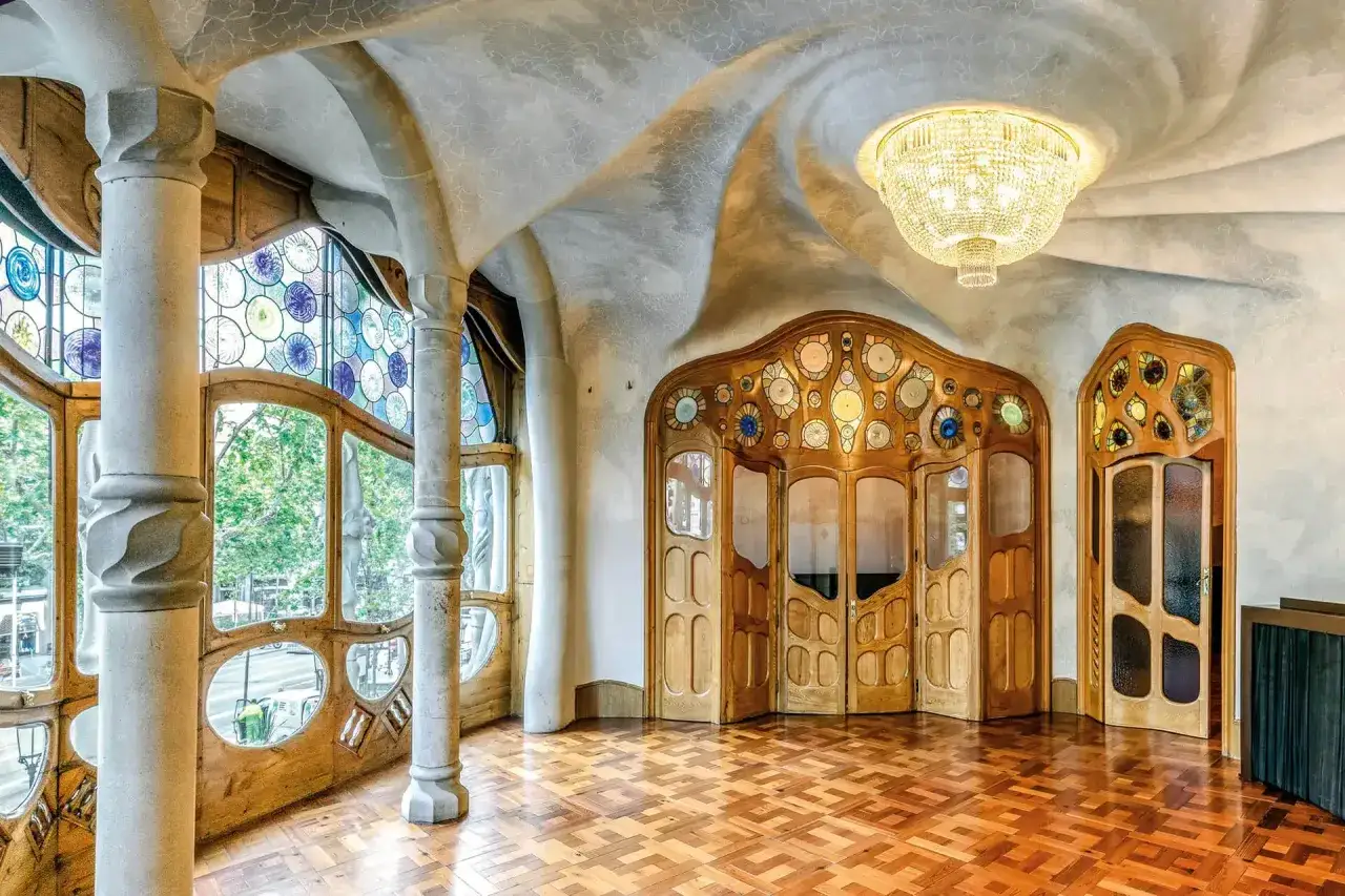 A grand interior with a contemporary art nouveau feel, featuring curved ceilings, stained-glass windows, and ornate wooden doors.