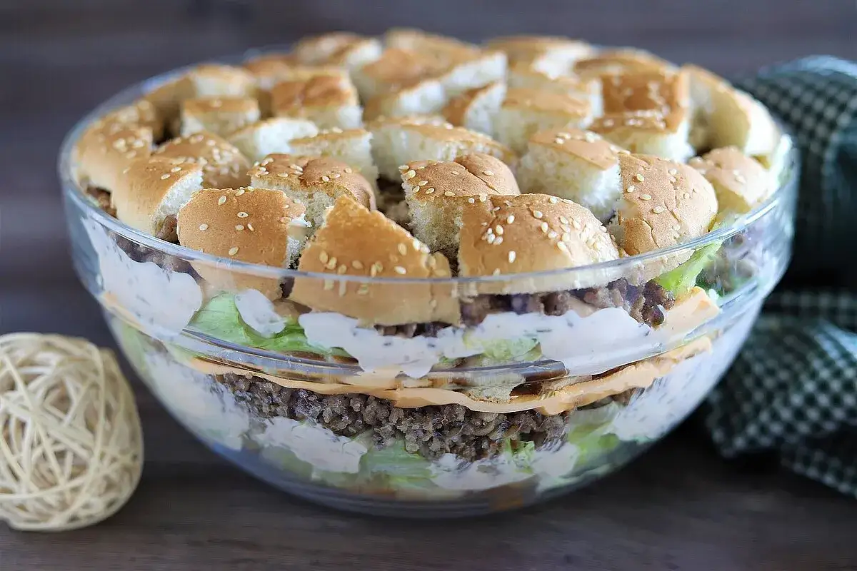 Schichtsalat im Glas, der wie ein Big Mac Salat aussieht, mit Hackfleisch, Salat, Käse und Brötchenstücken.