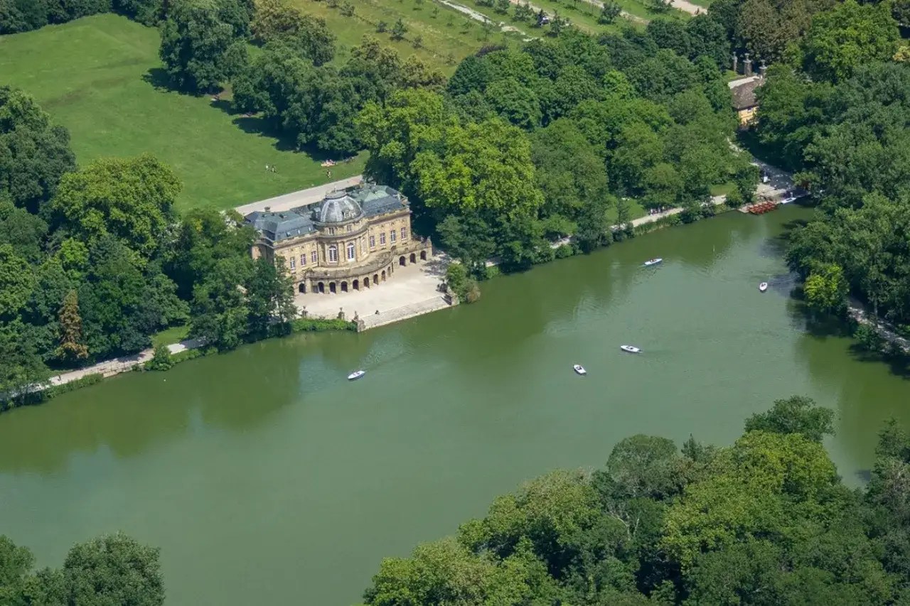 Schloss Monrepos am See, mit Booten auf dem grünen Wasser und üppigen Bäumen.