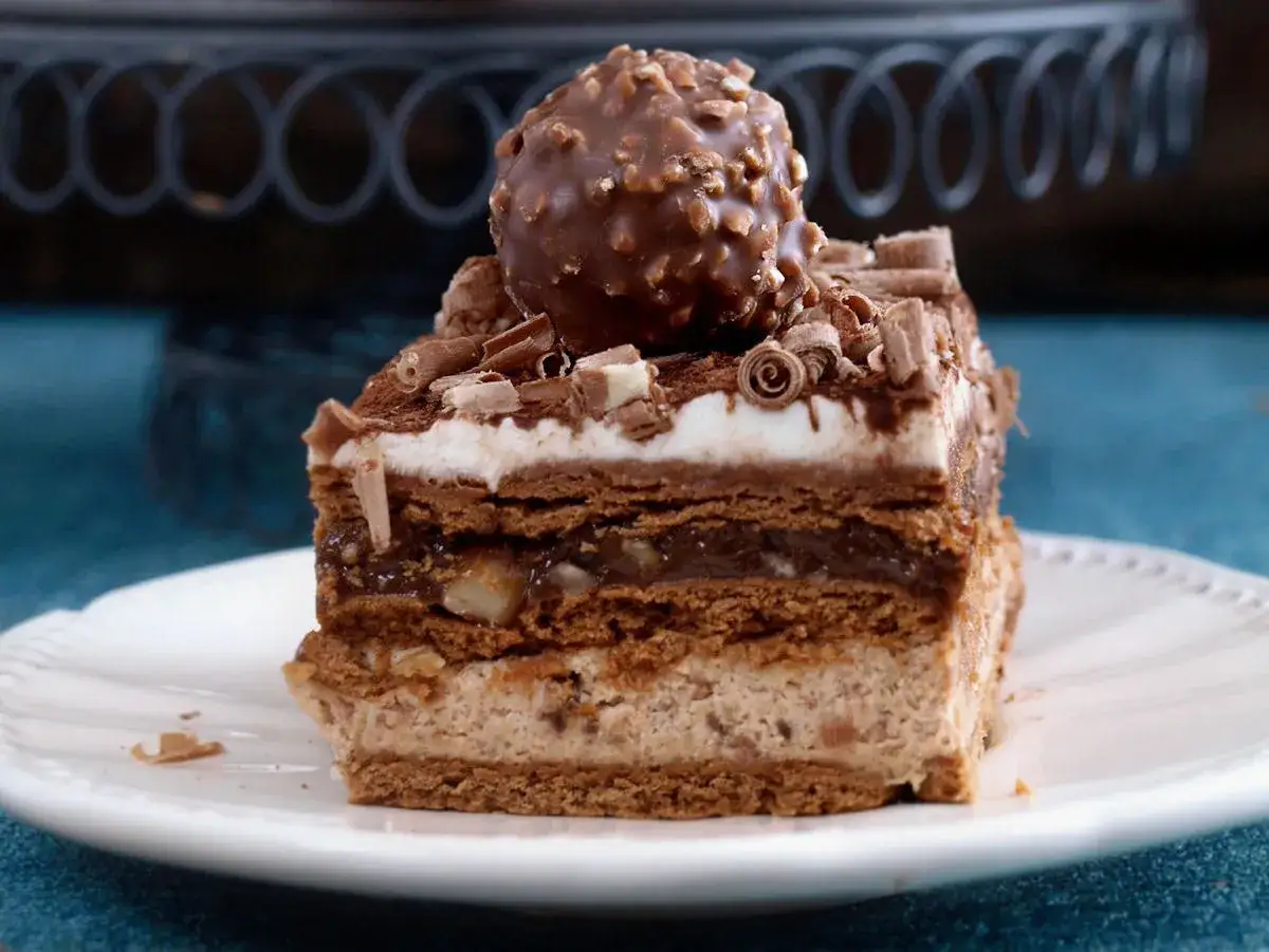 Pyszne, wielowarstwowe ferrero rocher ciasto z orzechami i czekoladą, zwieńczone kulką słynnych pralinek.
