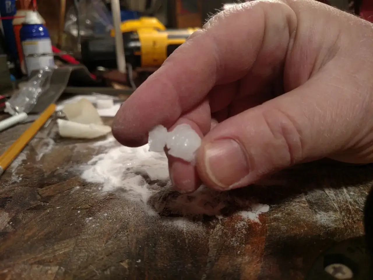 A hand holds a clump of hardened super glue, dusted with white powder. It looks like someone tried to sand super glue.
