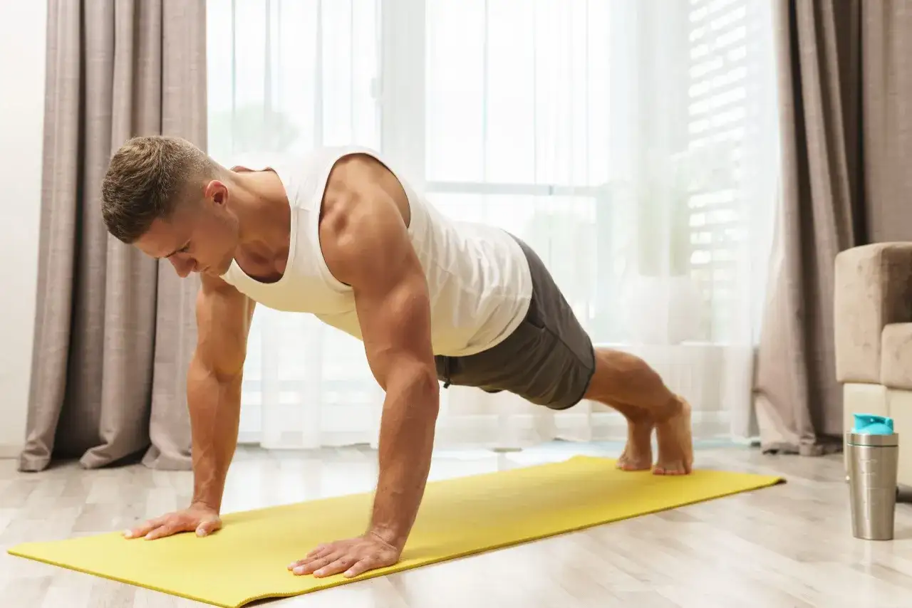 Mann macht Liegest&uuml;tze auf einer gelben Matte. Effektives Krafttraining zu Hause f&uuml;r einen fitten K&ouml;rper.