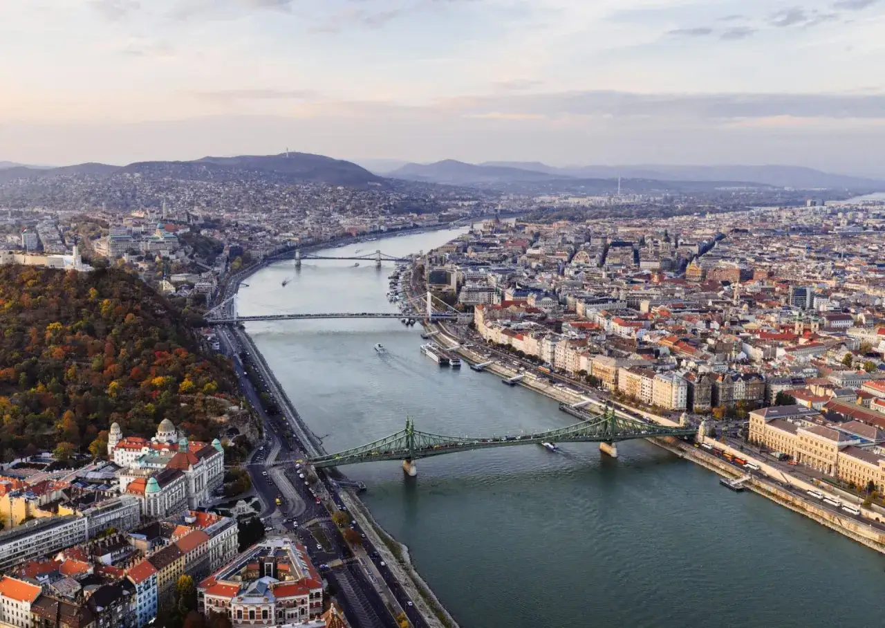 Widok na Dunaj i Budapeszt z lotu ptaka. Widać mosty, budynki i wzgórza. Idealne miejsce na rejs Dunajem w Budapeszcie.